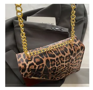 Detailed view of leopard print flap bag with gold chain strap on grey blazer fabric