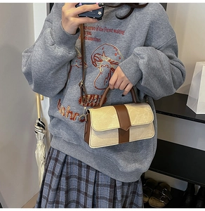 Detail van beige en bruine contrast handtas met gouden hardware en schouderband
