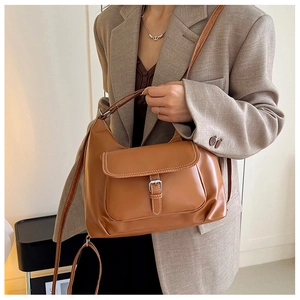 Détail d'un sac à bandoulière marron vintage avec surpiqûres blanches et boucle argentée