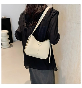 Detail view of cream white shoulder bucket bag with golden fashion hardware and stitching