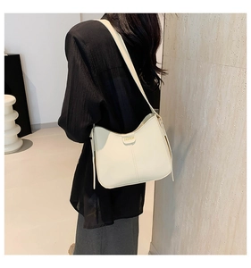 Detail of cream leather shoulder bag showing the golden FASHION embossing and smooth texture