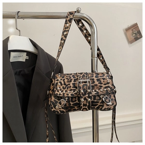Détail du sac léopard avec clous argentés et boucle métallique sur un cintre chic
