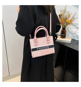 Detail of pink embroidered tote bag with textured surface and Fashion ribbon on person