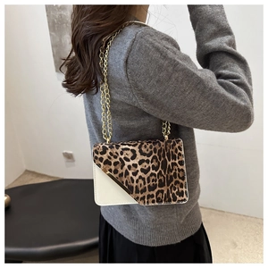 Detail of leopard print crossbody bag with gold metal trim and chain strap on model