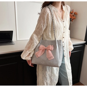 Detail der grauen Shopper Tasche mit rosa Schleife und gewebtem Schultergurt