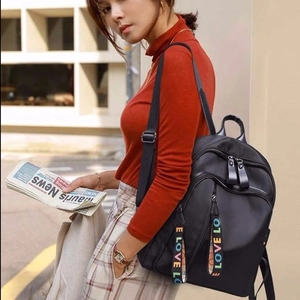 Detail of black nylon backpack with multi-pocket design and LOVE ribbon zipper pullers