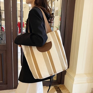 Striped canvas tote bag with brown leather trim and shoulder straps for daily commute
