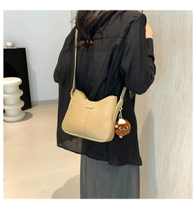 Detail of beige PU leather bucket bag with gold fashion plaque and plush monster charm