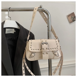 Détail d'un sac à bandoulière beige clouté avec rivets argentés et boucle métal Y2K