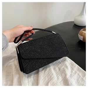 Détail de la pochette de soirée noire pailletée avec rabat rectangulaire et boucles dorées