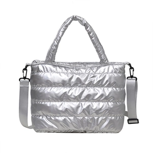 Silver quilted puffer tote bag with metallic finish and adjustable strap on white background