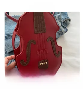 Detailed close-up of a red violin-shaped crossbody bag with gold metal studs and stitching