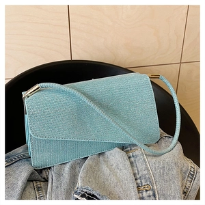 Gros plan sur le sac sous le bras en maille pailletée bleu clair avec boucles dorées