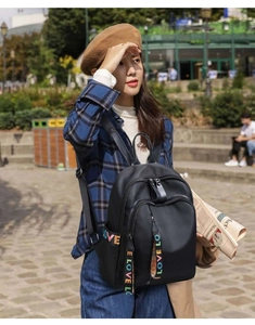 Detailed view of black nylon backpack featuring vibrant rainbow LOVE straps and side pockets