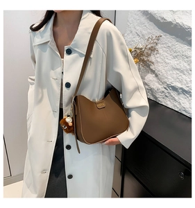Brown faux leather crossbody bag with fashion gold plate and plush charm on white trench coat