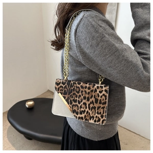 Detail view of leopard print crossbody bag with gold metal chain and asymmetric flap