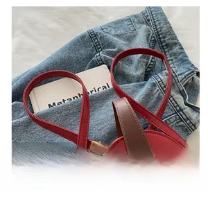 Detail of red violin-shaped bag showing brown handles and golden metal buckle hardware