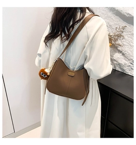 Detail of vintage brown bucket bag featuring gold fashion logo and fuzzy monster charm