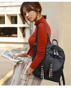Detail of black oxford backpack with multi-zipper design and colorful LOVE woven straps