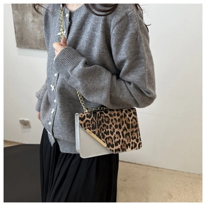 Detailed view of leopard print crossbody bag with gold chain strap on a model