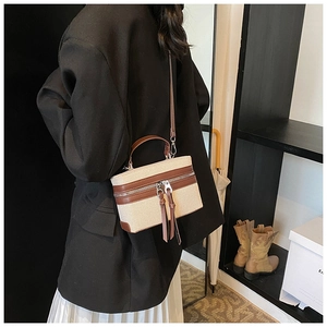Détail du sac boîte contrasté avec bordure en cuir marron et fermetures à glissière à glands