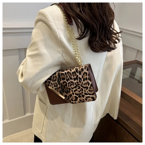 Detail of leopard print flap shoulder bag with gold chain strap on model shoulder