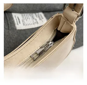 Close-up of silver metal zipper and stitching on a minimalist beige leather shoulder bag