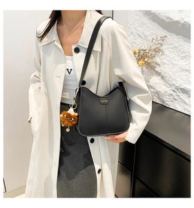 Detail of black leather crescent bucket bag with FASHION logo and plush monster charm