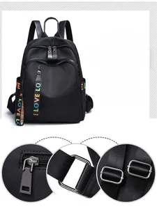 Detail view of the black nylon backpack's zipper pullers and polished metal hardware