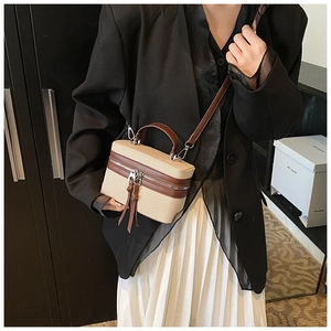 Détail du sac boîte en toile beige et cuir marron avec pompons et bandoulière