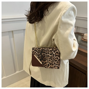 Detail view of leopard print crossbody bag with gold chain strap on a female model