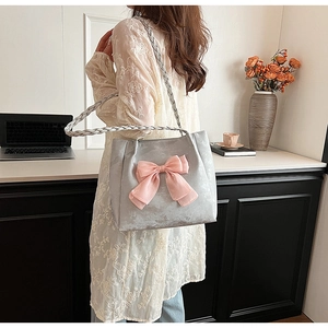Detail der silbernen Tragetasche mit rosa Schleife und geflochtenem Griff im Lifestyle