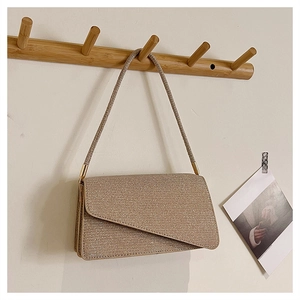 Détail d'un sac baguette pailleté doré avec rabat asymétrique suspendu au crochet