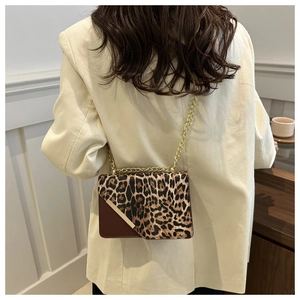 Close-up of leopard print crossbody bag with gold chain strap on a blazer