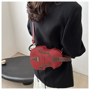 Detail shot of the red violin-shaped crossbody bag with golden hardware on a model