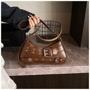 Macro detail of dark brown leather crescent bag with silver buckles and metal eyelets
