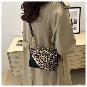 Detail of leopard print crossbody bag with gold chain strap on a trench coat