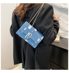 Detail showing back view of distressed blue denim crossbody bag with gold chain strap