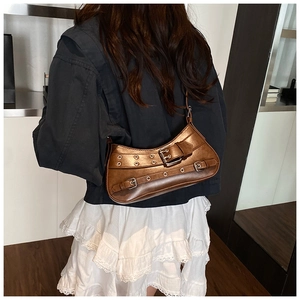 Close-up of a brown metallic Y2K shoulder bag with silver eyelets and buckle straps