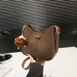 Brown vintage matte leather bucket bag with fashion metal plate and plush monster charm