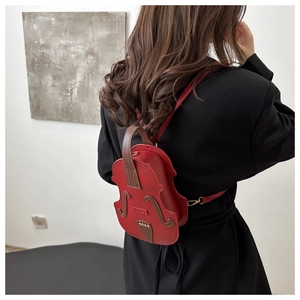 Detail view of violin-shaped crossbody bag in dark red matte leather on a model