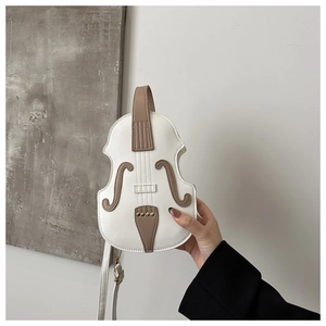 Detail view of violin-shaped white crossbody bag with brown trim and gold rivets