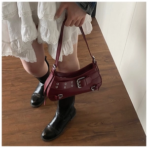 Close-up of a dark red retro underarm bag with silver buckles and punk style details