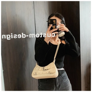 Chic cream crossbody bag with belt buckle details shown in a lifestyle mirror selfie