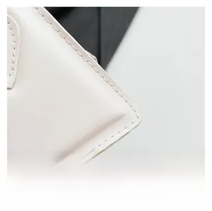 Gros plan sur la texture du cuir blanc et les coutures d'un petit sac minimaliste
