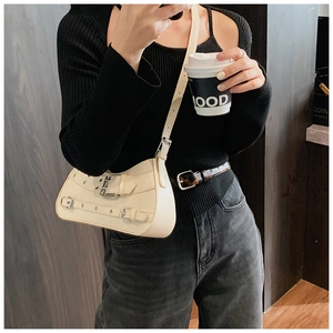 Chic cream crossbody bag with silver metal buckles shown in an urban street style setting