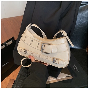 Detail of beige Y2K crescent bag with silver buckles and decorative eyelet straps