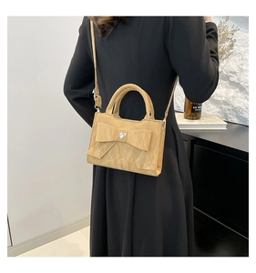 Détail d'un sac à main chic camel avec un grand nœud et une boucle cœur en strass sur modèle