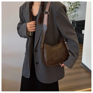 Detail of vintage brown bucket bag with a bohemian geometric woven wide strap on model