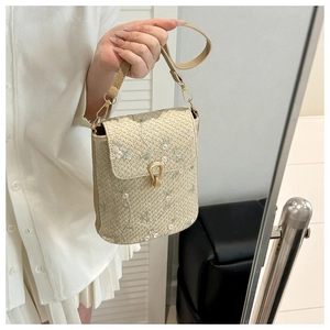 Detail of woven texture and floral embroidery on a compact cream-colored crossbody bag